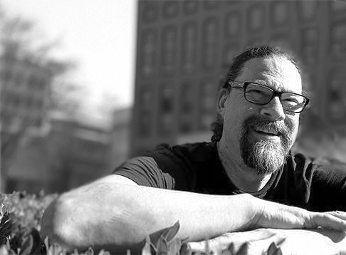 Black and white photo of Joseph Kakwinokanasum with Vancouver Public Library building showing in a blurred background